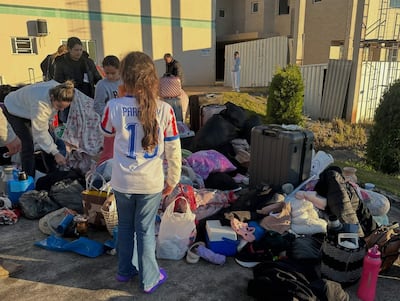 Niña con camiseta de Paraguay y número 10, rodeada de mujeres que organizan pertenencias en un ambiente de asistencia humanitaria.