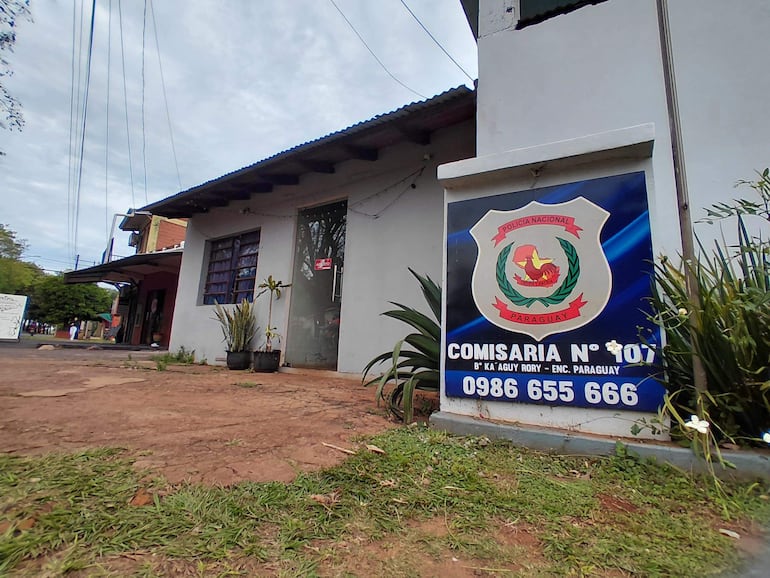 Fachada de la Comisaría N° 107 con cartel de la Policía Nacional de Paraguay y plantas en el frente.