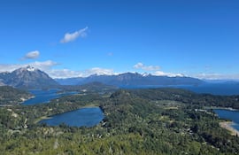 Paisaje montañoso con grandes montañas y lagos rodeados de vegetación verde; escena serena y natural sin personas presentes.
