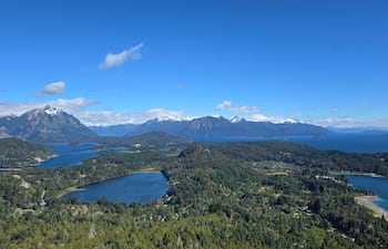Paisaje montañoso con grandes montañas y lagos rodeados de vegetación verde; escena serena y natural sin personas presentes.