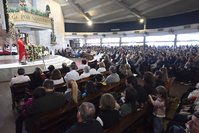 Congregación masiva en iglesia, sacerdote de pie frente a micrófono, asistentes en reflexión y oraciones, ambiente solemne.