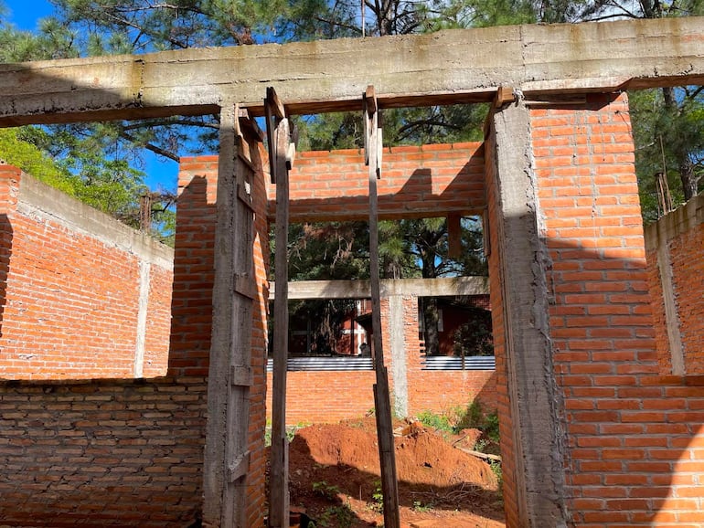 Estructura de ladrillos y columnas de concreto en construcción, sin personas visibles, con cielo despejado al fondo.
