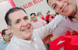Cubilla en camisa blanca y Cartes en camisa a rayas, sonriendo juntos en un salón decorado con elementos rojos.