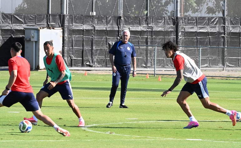 Gustavo Alfaro observa el entrenamiento de jugadores, entre ellos Alejandro Romero Gamarra Kaku, en un campo de césped.