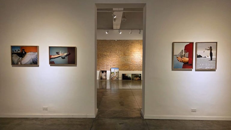 Interior de galería de arte con cuatro obras enmarcadas en paredes blancas y ladrillos expuestos.