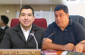 Diego Candia con chaqueta oscura y pin en la solapa se abraza con un hombre de camiseta negra en oficina.