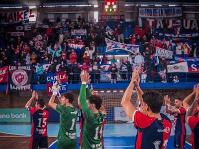 Jugadores de Cerro Porteño con camisetas verdes y azules celebran, rodeados de aficionados con banderas en un ambiente deportivo vibrante.
