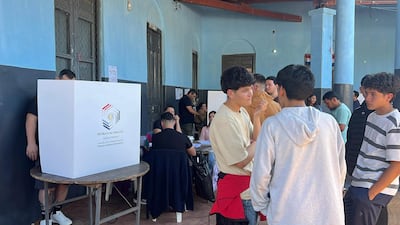 Grupo de jóvenes discutiendo en un ambiente electoral, rodeados de mesas y una urna de votación con el emblema de Paraguay.