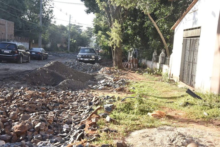 Calle del Abasto con material de construcción, varios coches oscuros estacionados y una casa con puerta negra.