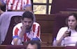Raúl Benítez con camiseta roja y blanca, Johanna Ortega con camiseta blanca sosteniendo un vaso, en un recinto legislativo.