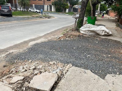 Zona de obras con escombros y piedras, un vehículo estacionado y una figura alejada con ropa clara.