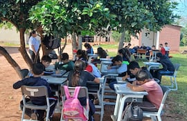 Alumnos de la escuela y Colegio República del Paraguay de Yaguareté Forest, San Pedro, dan clase bajo los árboles.