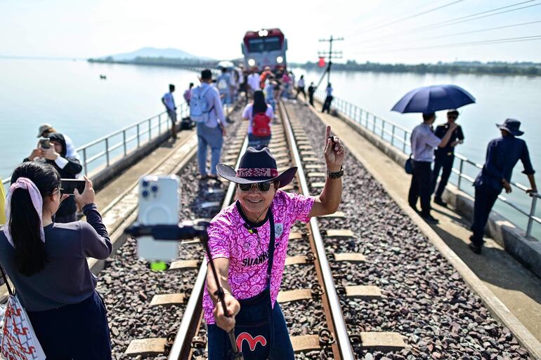 Un hombre se toma una foto en las vías del llamado "tren flotante de Tailandia".