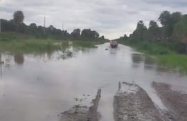 Un vehiculo trata de pasar por un camino inundado.