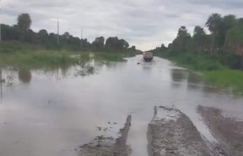 Un vehiculo trata de pasar por un camino inundado.