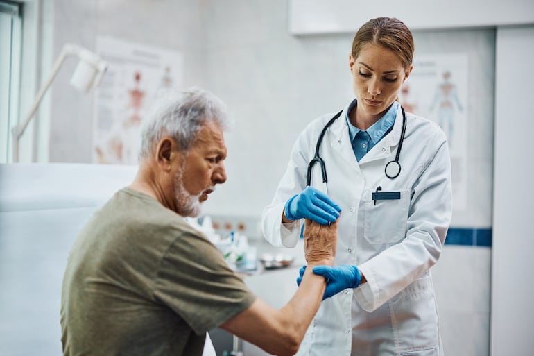 Hombre con artritis reumatoide es analizado por una doctora.