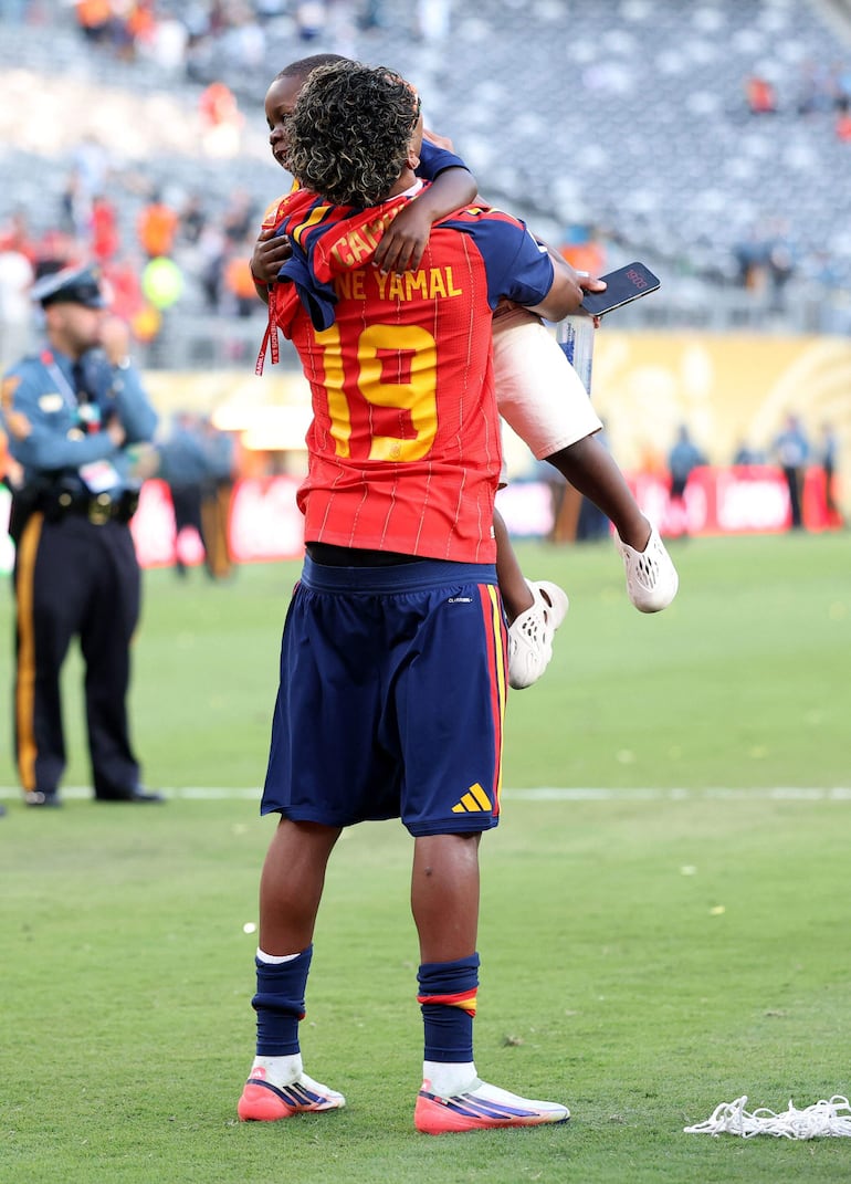 Lamine Yamal con su hermanito Keyne en brazos, en el campo de juego del MetLife Stadium en East Rutherford, New Jersey. (Justin Setterfield/Getty Images/AFP)