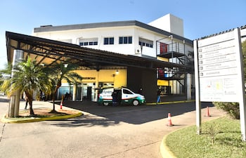 Ambulancia de Epem en entrada del hospital, con árboles pequeños y letreros visibles de urgencias bajo un cielo claro.