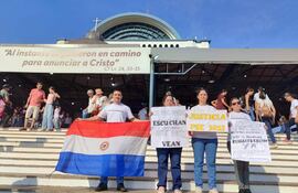 Exfuncionarios de Itaipú se llegaron a la Basílica con carteles pidiendo una respuesta del presidente de la República.