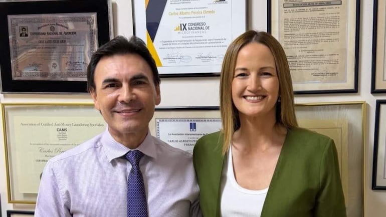 Carlos Pereira Olmedo con camisa clara y corbata, junto a Soledad Núñez en blusa blanca con abrigo verde, ambos sonriendo en una oficina.