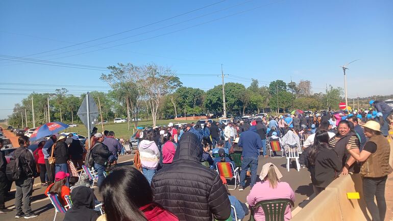 Grupo de docentes en Coronel Oviedo, algunos con chaquetas y gorras, en actitud de espera durante movilización en la vía pública.