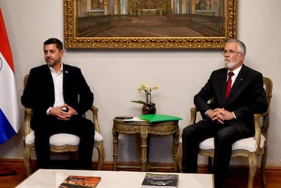 Marcondes de Carvalho y Ramírez Lezcano en ambiente formal, el primero habla mientras el segundo escucha con atención, rodeados de documentos.