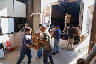 Hombres en camiseta clara y oscura levantan cajas en un lugar de trabajo iluminado y colaborativo.