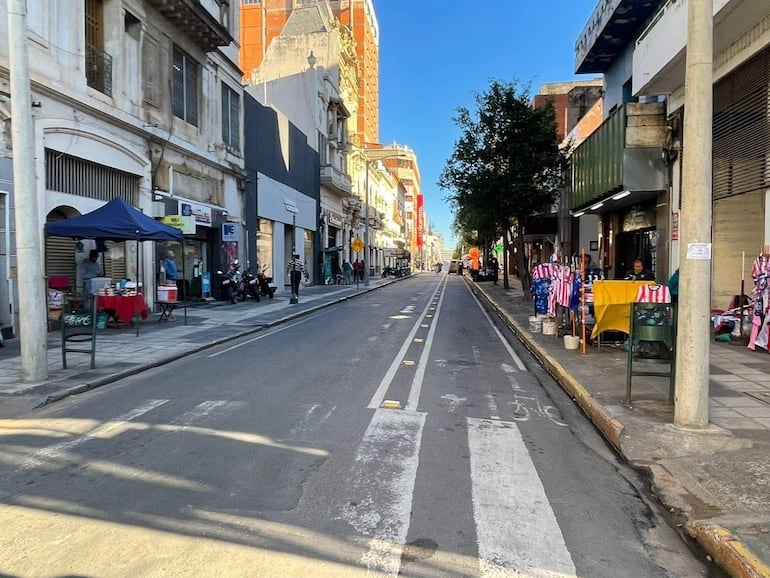Calle urbana vacía con un puesto de venta de camisetas rojas y blancas del Club Atlético Nacional de Paraguay.