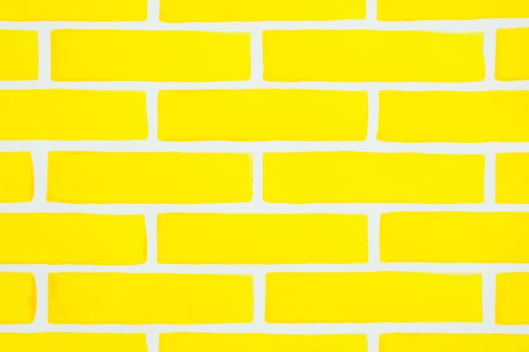 Pared amarilla de ladrillos pintados, sin elementos humanos o decorativos, con un fondo uniforme y recto.