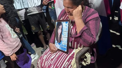 Mujer con blusa de rayas sostiene un cuadro con foto de joven mientras otros manifestantes piden justicia en la protesta.