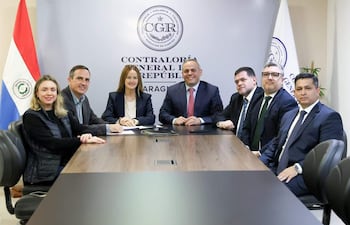 Camilo Benítez Aldana y Soledad Núñez en reunión formal, con expresiones tranquilas, en entorno de oficina decorado con una bandera paraguaya.
