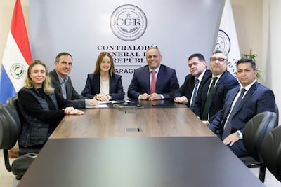 Camilo Benítez Aldana y Soledad Núñez en reunión formal, con expresiones tranquilas, en entorno de oficina decorado con una bandera paraguaya.