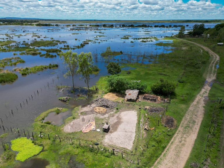 Paisaje natural inundado con vegetación dispersa y una edificación rústica en un entorno rural afectado por la crecida del río.