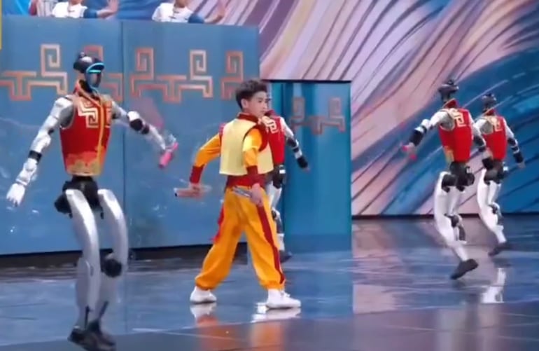 Robots humanoides bailan con un adolescente chino. (captura de video)