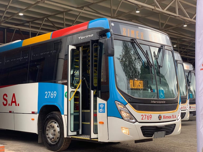 Autobús de Ximex S.A. estacionado, colores azul y rojo, con la entrada abierta en un garaje.