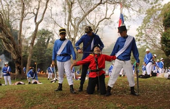 Hombres vestidos de azul y rojo, en un ambiente natural, representando una batalla, con posturas de confrontación.