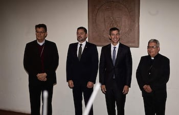 Santiago Peña y Adalberto Martínez Flores brindan sonrisas, mientras otros hombres observan con seriedad en un entorno formal.