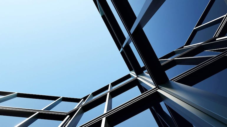 Estructura arquitectónica moderna con diseño contemporáneo, ventanas de vidrio y cielo claro al fondo.