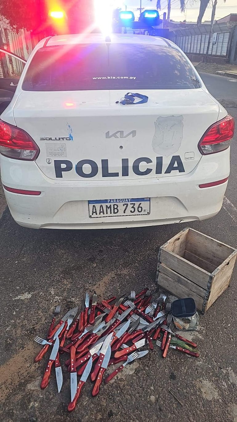 Cuchillos y tenedores esparcidos en el suelo cerca de un vehículo policial en una escena de intervención.