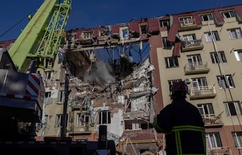 Bomberos ucranianos frente a un edificio residencial gravemente dañado durante un bombardeo ruso hoy en Odesa.