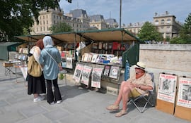 Un librero de 65 años sentado en su puesto, vendiendo libros antiguos y carteles antiguos, en la orilla izquierda del río Sena en París.