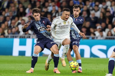 El delantero francés del Real Madrid, Kylian Mbappé (C), se escabulle entre el delantero español del Celta de Vigo, Pablo Durán (I), y el centrocampista español, Miguel Román, durante el partido de fútbol de la liga española entre el Real Madrid CF y el RC Celta de Vigo, en el Estadio Santiago Bernabéu en Madrid.