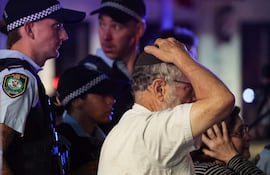 Un miembro de la comunidad judía reacciona mientras camina con la policía hacia el lugar de un tiroteo en Bondi Beach, Sídney.