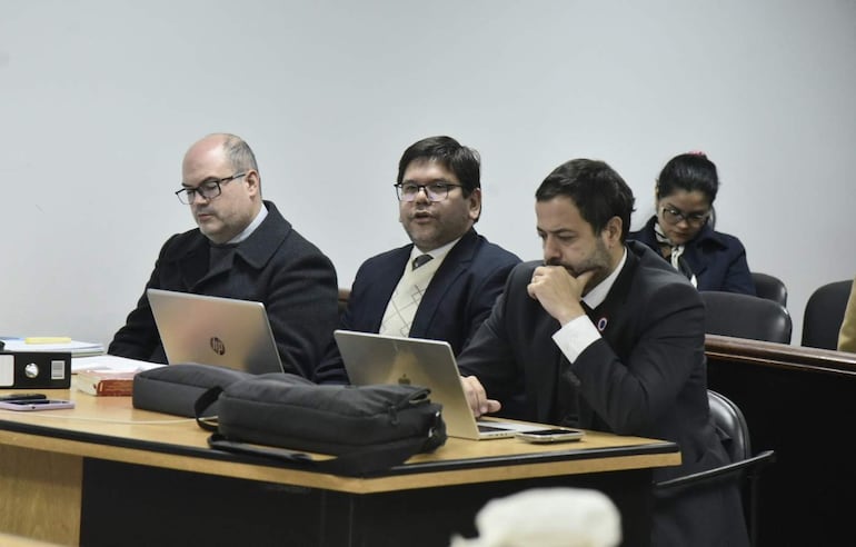 Fernando Meyer, Jorge Arce y Francisco Cabrera sentados en mesa con expresión seria, en un entorno de discusión formal con computadoras y documentos.