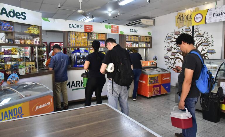 Una fila de personas esperando para pagar en la caja de la cantina. 
