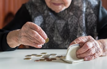 Una adulta mayor cuenta las monedas que cargará en su monedero.
