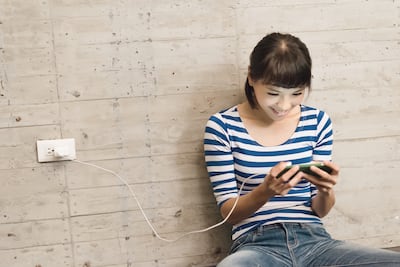 Mujer usa su smartphone mientras este está enchufado.