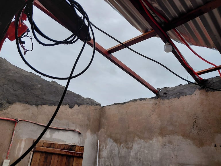 Techo de construcción con estructura metálica expuesta y cables colgando, en un día nublado.