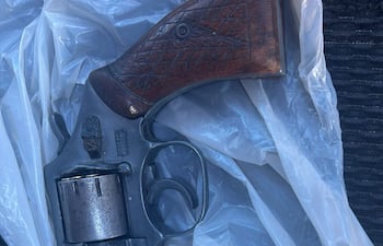 Un revólver reposado sobre una bolsa plástica blanca en el interior de un vehículo, sin presencia de personas.