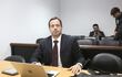 Francisco Cabrera en traje oscuro y corbata delgada, concentrado en su portátil, en un ambiente sobrio con otra persona al fondo.